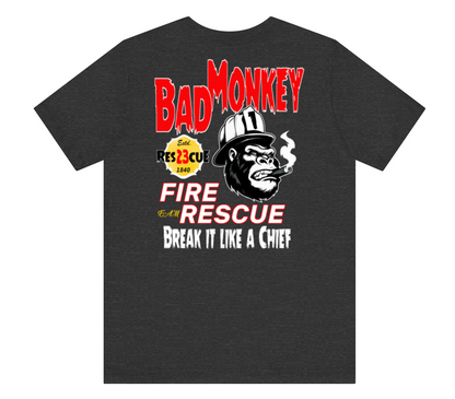 A dark heather gray t-shirt featuring a graphic print of a smoking gorilla wearing a firefighter helmet, with the text 'BAD MONKEY' in red, 'FIRE AND RESCUE' in red and white, and 'BREAK IT LIKE A CHIEF' in white.