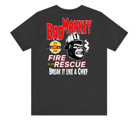 A dark heather gray t-shirt featuring a graphic print of a smoking gorilla wearing a firefighter helmet, with the text 'BAD MONKEY' in red, 'FIRE AND RESCUE' in red and white, and 'BREAK IT LIKE A CHIEF' in white.